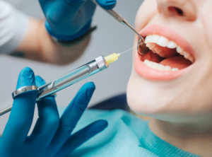 Dentist in blue gloves using a dental drill and mirror on a patient’s open mouth during a dental procedure.